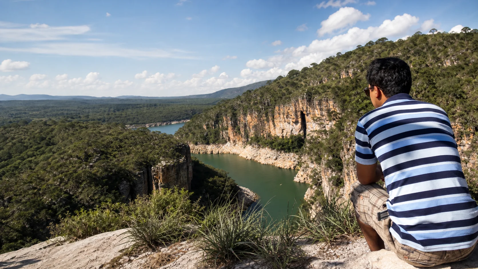 Guilherme Rocha observando uma paisagem de cânions e água sob o céu aberto